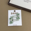 Detail of mint green floral bow hair clips with knitted texture on display card - Teardrop Floral Style