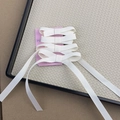 Detail view of four white ribbon bow hair clips on pink card in a beige woven tray - Off White