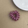 Gros plan d'un chouchou spirale violet style cordon de téléphone sur fond minimaliste - Rouge