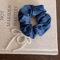 Elegant navy denim scrunchie featuring a white faux pearl bow pendant on a book - Denim Texture