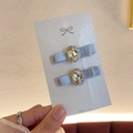 Détail de barrettes nœud bleu-gris avec strass ovales sur carte de présentation - Bleu