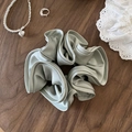Elegant Morandi green scrunchie made of premium satin fabric on dark wood background - Green