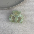 Detail view of light green marble texture acetate hair claw clip on white fabric background - Green