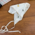 Dettaglio della bandana bianca con ricami floreali e bordi in pizzo su fondo legno - Fazzoletto Triangolare Ricamato