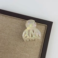 Detail shot of pearlescent acetate hair claw clip with iridescent finish on wooden display - Mermaid Color