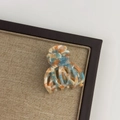 Top view of medium acetate hair claw clip with colorful marble pattern on a display tray - Mint Blue Brown