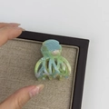 Detail of medium acetate hair claw with green marble texture on burlap display mat - Green Series