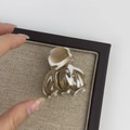 Close-up of medium acetate hair claw clip with amber marble texture on display board - White Coffee Series
