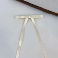 Dettaglio del fermaglio per capelli a fiocco in raso crema con elegante coda lunga - Beige