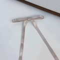 Detailed view of the elegant satin bow hair clip with long ribbons in soft champagne pink - Purple Pink