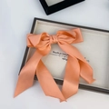 Elegant coral pink satin bow hair clip with flowing ribbons on a minimalist white base - Pink Orange