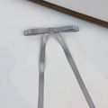Dettaglio di un fermaglio per capelli con fiocco in raso grigio e lunghi nastri fluenti - Grigio