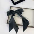 Elegant large black satin bow hair clip with long ribbons on a decorative cream tray - Black