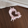 Detail einer rosa Satin-Herz-Haarklammer mit Schleifen auf einem gemütlichen Hintergrund - Rosa