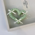 Detail view of light green silk ribbon heart hair claw with white bows on metal base - Green