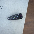 Detailed shot of black hair clip with colorful hand-painted polka dots on fabric book - Small Black Triangle