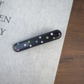 Gros plan sur une barrette noire ornée de pois colorés en 3D sur fond texturé sobre - Noir Large Droit