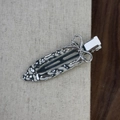 Dettaglio del fermaglio per capelli in metallo argento con fiocco e finitura martellata - Stile Fiocco Strutturato