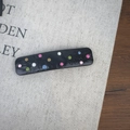 Détail d'une pince à cheveux noire avec des pois colorés 3D sur un tissu texturé - Rectangle Noir