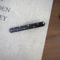 Vue détaillée de la pince à cheveux noire à pois colorés sur un tissu texturé - Noir Fin Droit