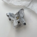 Macro view of grey marble texture butterfly hair claw clip with golden spring mechanism - Ink Grey and White