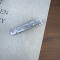 Gros plan d'une pince à cheveux argentée à pois multicolores sur un tissu texturé - Argent Large Droit