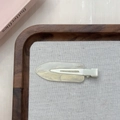 Dettaglio di un fermaglio per capelli bianco crema con glitter su vassoio in legno - Bianco Argento