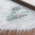 Detailed view of mint green acetate hair claw clip featuring starfish and star patterns - Blue