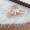 Close-up of peach acetate starfish hair claw clip with glitter accents and rhinestones - Pink