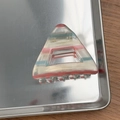 Détail d'une pince à cheveux triangulaire avec des rayures colorées en acétate sur plateau - Bleu Rose Translucide