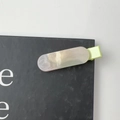 Detalle de una pinza de resina con textura de mármol crema y brillos sobre tarjeta negra - Verde