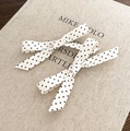 Dettaglio ravvicinato di fermagli per capelli con fiocchi a pois e nastri lunghi su libro - Fiocco per capelli