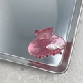 Dettaglio di una molletta per capelli rosa con motivo a pesci su vassoio in metallo - Rosa