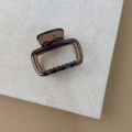 Detailopname van een amberkleurige haarklem op een getextureerde beige linnen stof - Vierkant / Amber Donkerbruin