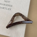Detail van een doorschijnende koffiekleurige driehoekige haarklem met een zwarte metalen veer - Driehoek / Amber Donkerbruin