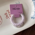 Detalle de dos gomas de pelo en espiral moradas en tarjeta con patrones florales - Serie Púrpura
