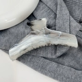 Detail van grote haarklem met inkt-marmer effect op een grijze stoffen ondergrond - Hanger Stijl