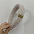 Detalle de diadema de lana de cordero con una placa de metal dorada en beige claro - Azul Pálido