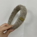 Detalle de una diadema de peluche gris con una etiqueta metálica dorada - Marrón
