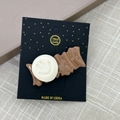 Nahaufnahme einer braunen Wellenhaarspange aus Harz mit Smiley auf Kartonverpackung - Weißer Smiley