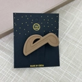 Gros plan d'une barrette à cheveux en forme de note de musique marron mat sur carte - Note De Musique Café