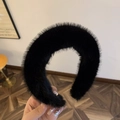 Dettaglio di un cerchietto in finta pelliccia nera che mostra la texture morbida e il volume - Nero