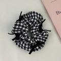 Dettaglio di elastico pied de poule con fiocco di velluto e perla su uno sfondo morbido - Plaid Bianco e Nero