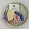 Detalle de cuatro gomas de pelo suaves y coloridas en bandeja con tarjeta de exhibición - Multicolor