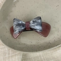 Detail shot of grey marble texture bow hair clip with gold logo on a ceramic plate - 3D Bow-Pink Gray