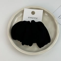 Detalle de un coletero de terciopelo negro suave con elástico en un entorno minimalista - Negro