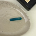 Detail of dark cyan acetate hair clip with golden France Handmade text on ceramic tray - Green