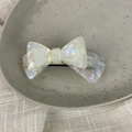 Detail view of pearlescent acetate bow hair clip with branding on a ceramic plate - 3D Bow-Mermaid Color