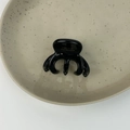 Detail of black acetate hair claw with gold France Handmade logo on beige ceramic plate - Black