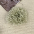 Vue détaillée d'un chouchou en peluche vert clair sur un fond de tissu beige texturé - Vert